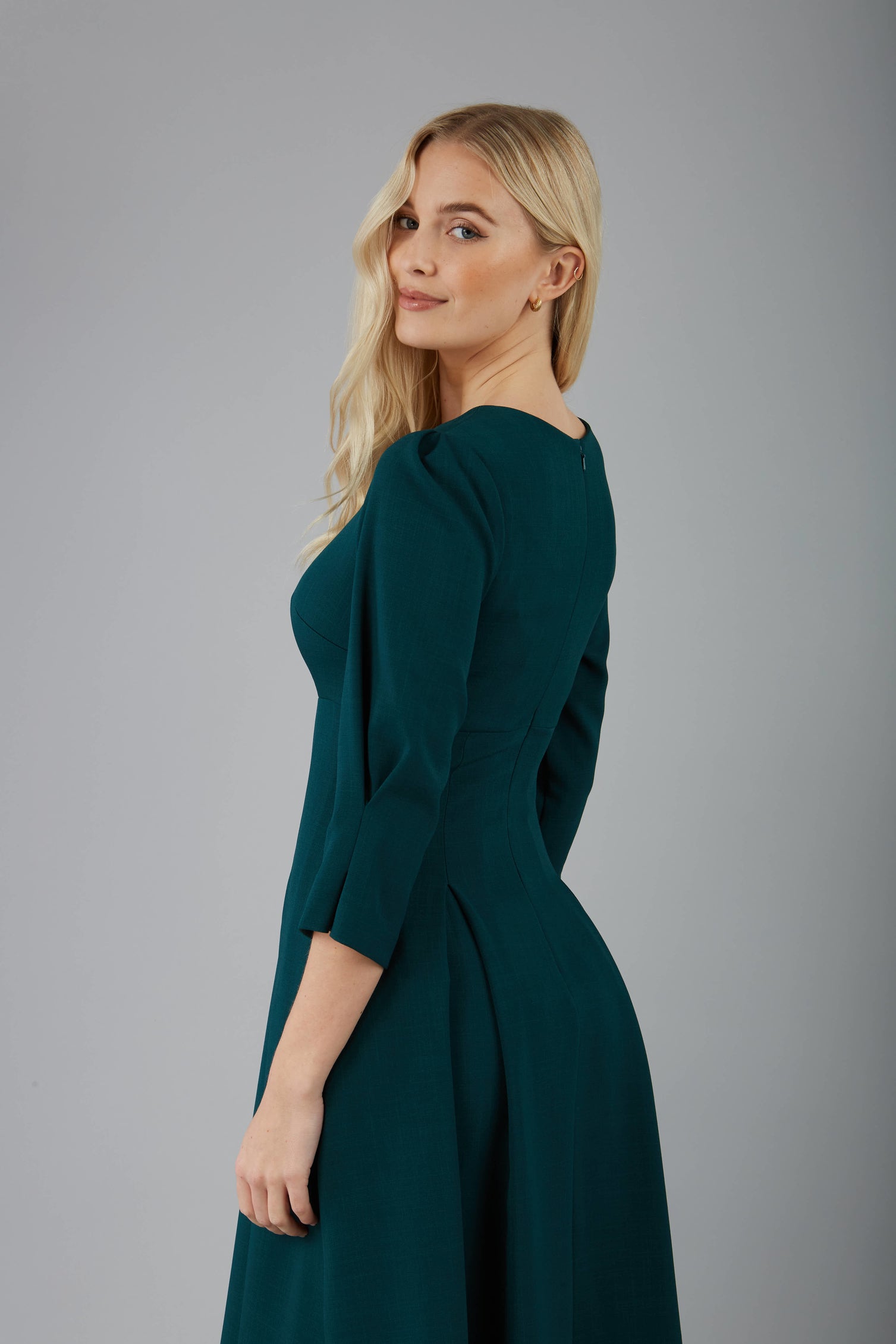blonde model is wearing diva catwalk harpsden a-line skirt 3/4 sleeve swing dress with rounded neckline in forest green back