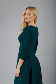 blonde model is wearing diva catwalk harpsden a-line skirt 3/4 sleeve swing dress with rounded neckline in forest green back