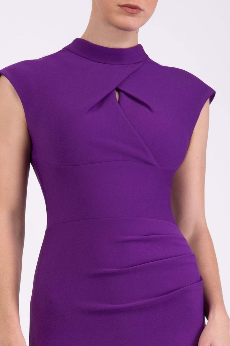 brunette model wearing diva catwalk beyonce pencil fitted dress with high neckline without sleeves with a wide band and pleating across the tummy area with a crossed detail neckline in royal purple front