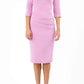 A model is wearing a three quarter sleeve pencil dress with a round neckline and bow detail at the front in pink