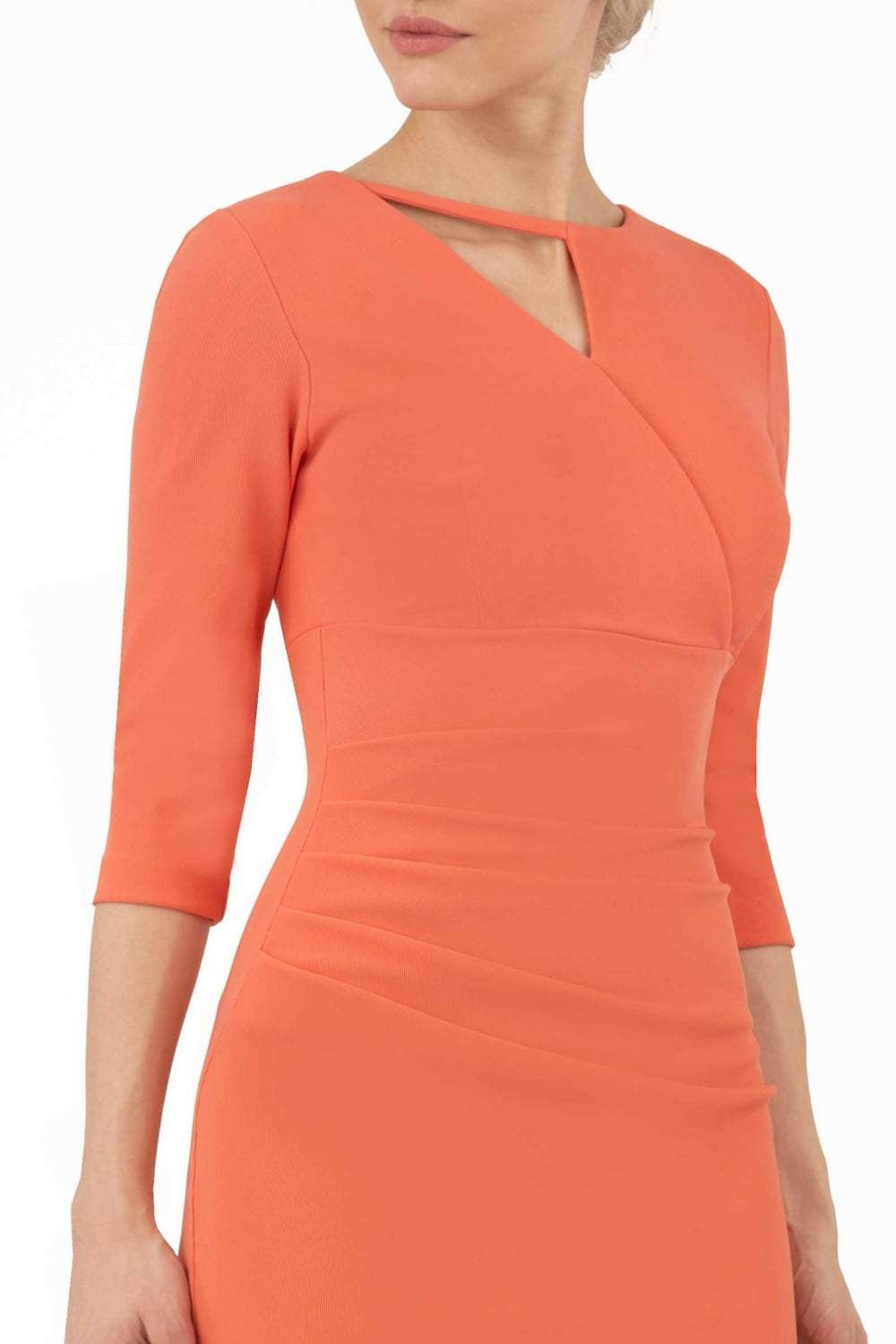 model wearing diva catwalk helston peach pencil dress with sleeves and cut out detail on the neckline front