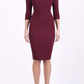 brunette model wearing diva catwalk best selling lydia pencil sleeved dress with slit at the neckline and pleating across the tummy in colour cabaret burgundy front