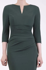 brunette model wearing diva catwalk best selling lydia pencil sleeved dress with slit at the neckline and pleating across the tummy in colour deep green front