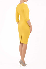 brunette model wearing diva catwalk best selling lydia pencil sleeved dress with slit at the neckline and pleating across the tummy in colour mustard yellow back