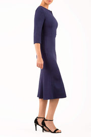 blonde model is wearing diva catwalk senne midaxi sleeved dress with fishtail and rounded neckline with a slit in the middle in navy blue side