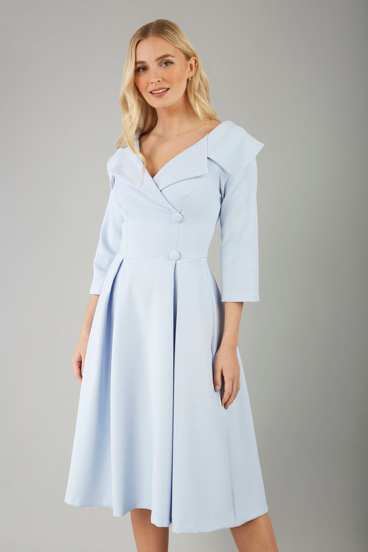 model is wearing a sleeved beige oversized collar swing dress with button detail at the front and pockets in the skirtmodel is wearing diva catwalk gatsby swing dress with pocket detail and wide v-neck collar and buttons down the front panel in celestial blue front