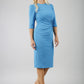 blonde model is wearing diva catwalk lucretis rounded neckline sleeved pencil dress with rushing on shoulders and rushed detail on a side of a waistline in malibu blue front
