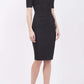 blonde model is wearing diva catwalk lydia short sleeve pencil fitted dress in black colour with rounded neckline with a slit in the middle front