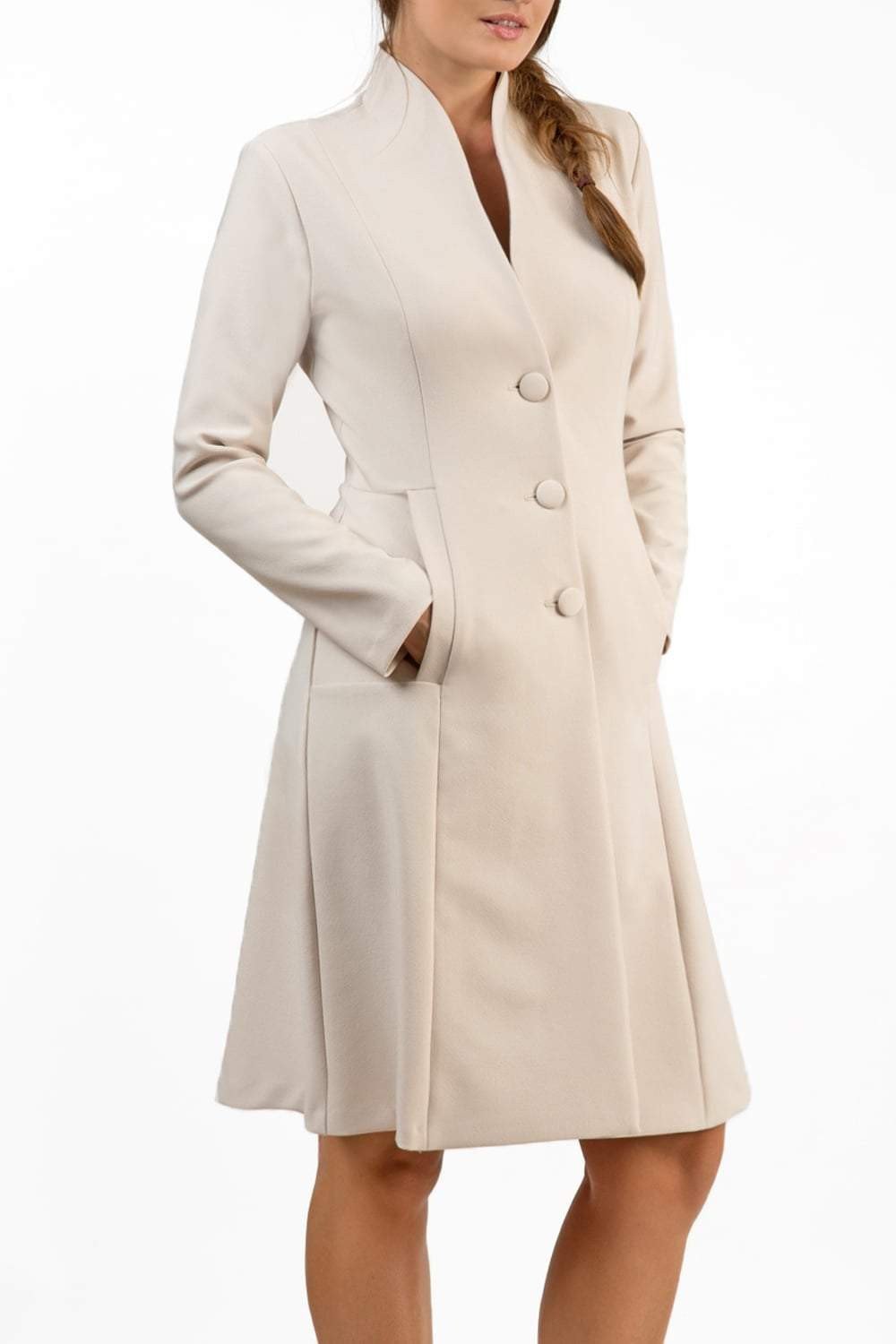 brunette model wearing diva catwalk couture fine raquella coat with buttons across the front and long sleeves with high neck and pockets in sandy cream colour front