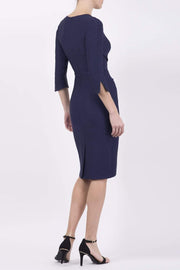blonde model wearing seed tuscany pencil fitted dress in navy blue colour with a split in the neckline and split detail on sleeves back